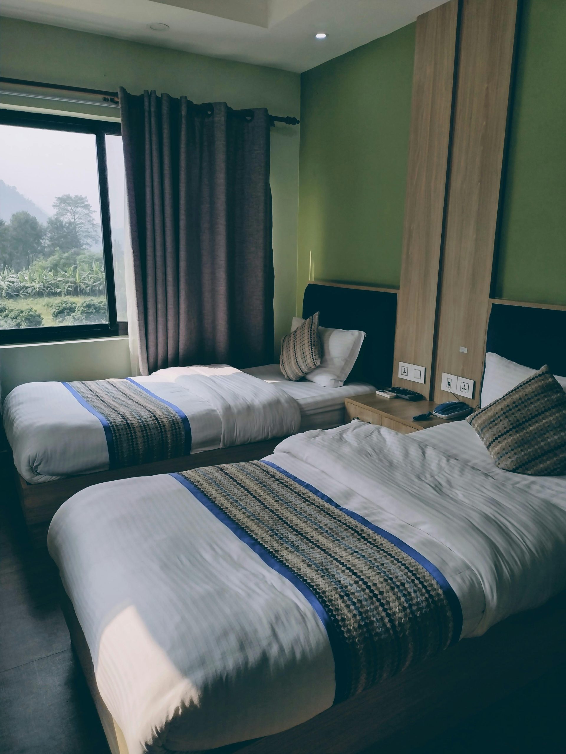 Luxurious hotel room interior with twin beds and a scenic window view.